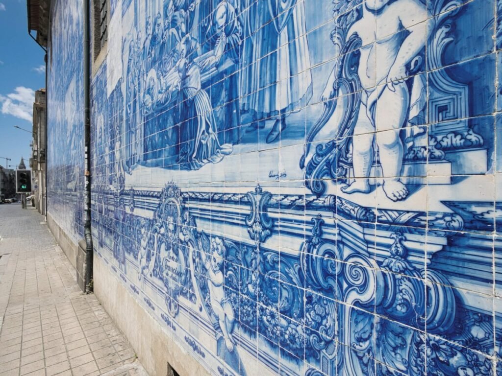 Porto, Portugal: A Slow Travel Guide The magnificent exterior facade of a famous historic church in Porto, completely covered in intricate traditional blue and white azulejo tile murals under bright daylight.