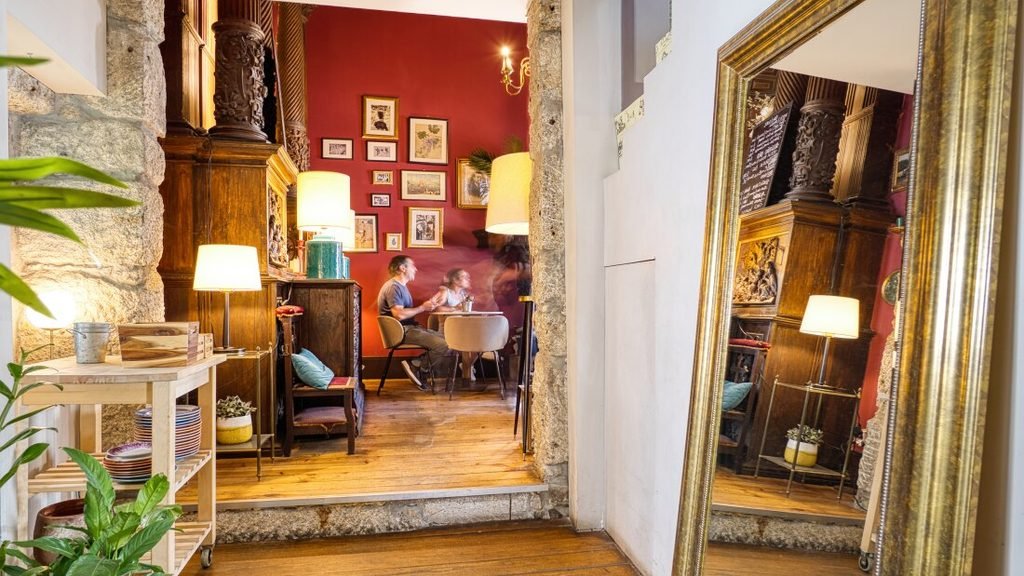 Solo Female Travel in Porto: 3 Day Slow-Travel Itinerary The intimate interior of Capela Incomum wine bar, showing guests sitting at tables in the distance with a large mirror on the right wall capturing the warm, candlelit atmosphere.