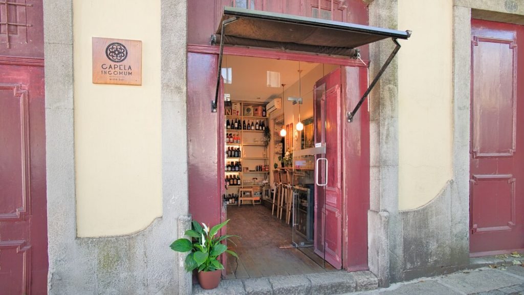 Solo Female Travel in Porto: 3 Day Slow-Travel Itinerary The charming exterior stonework front entrance of Capela Incomum wine bar, framed by a quiet pedestrian sidewalk and a massive leafy tree in central Porto.