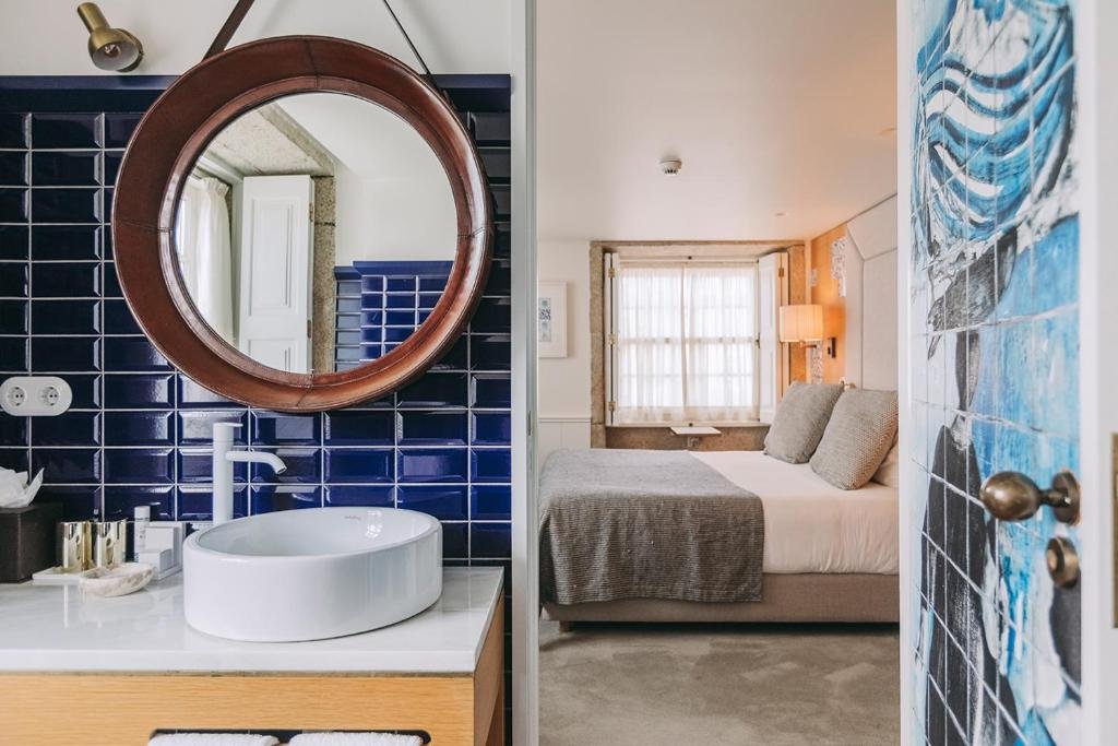 A Guide to the Best Day Tours From Porto An interior perspective of a boutique guest room at Gran Cruz House in Porto, looking from the stylish bathroom doorway into the main hotel bedroom area."