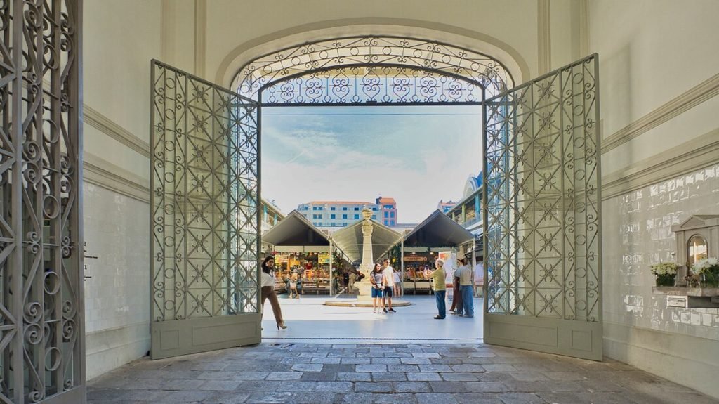 Solo Female Travel in Porto: 3 Day Slow-Travel Itinerary The grand historic stone entrance and monumental front gate facade of the neoclassical Mercado do Bolhao on a bright day in central Porto.