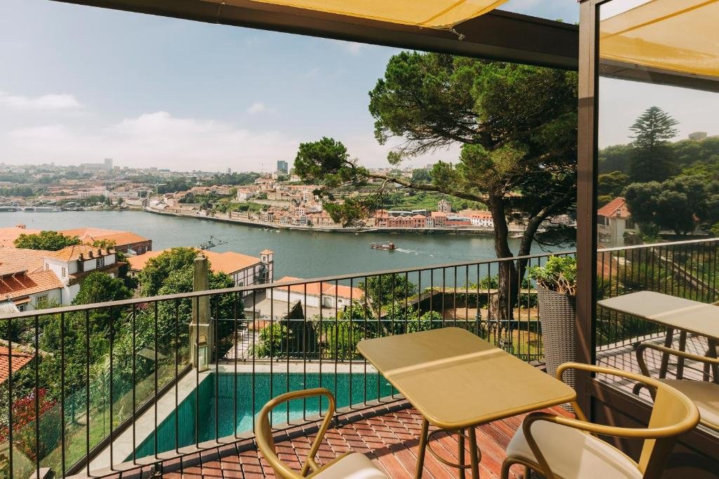 A Guide to the Best Day Tours From Porto A view from a private guest balcony at the Torel Avantgarde hotel in Porto, showcasing an expansive and beautiful overview of the winding Douro River and the historic city landscape.